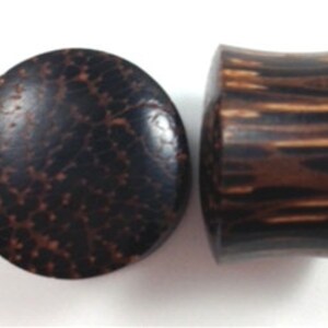 May include: Pair of wooden ear gauges, one with a smooth, dark brown finish and the other with a striped, light brown and dark brown finish.