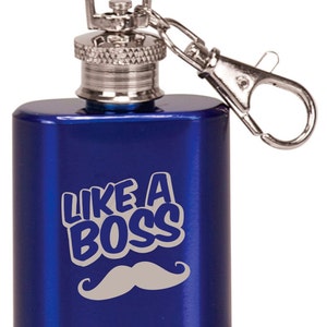 Op de afbeelding: Een blauwe metalen fles met een zilveren dop en een sleutelhanger. De fles heeft de tekst "Like a Boss" en een zilveren snor erop gedrukt.