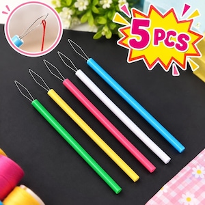 May include: A set of 5 pieces of needle threaders with colorful plastic handles in green, yellow, pink, white, and blue. Each tool features a thin, diamond-shaped wire loop at the end for threading needles. The text 5 PCS is visible.
