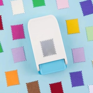 May include: A white and light blue craft punch tool designed to create rectangular shapes with scalloped edges, surrounded by numerous small, colorful paper cutouts in shades of yellow, green, purple, orange, red, and white.