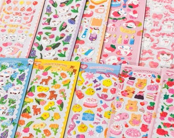 May include: Ten vertical sticker sheets featuring various colorful designs including white cats, tulips, yellow chicks, teddy bears, cakes, and ribbons. Each sheet has a scalloped edge and the text moomogmog printed at the top.