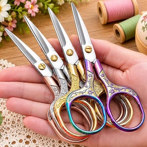 May include: A set of four small metal embroidery scissors with sharp silver blades and ornate handles. The handles feature embossed floral patterns and come in various metallic finishes including rose gold, silver, gold, and a multi-colored iridescent purple.