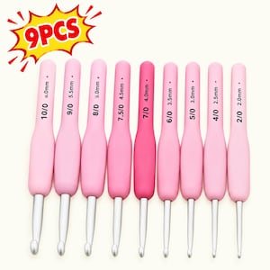 May include: A set of 9 crochet hooks with pink handles, each featuring a silver metal hook and printed size markings ranging from 2.0mm to 6.0mm, plus 7.5/0, 8/0, 9/0, and 10/0. The text 9PCS is displayed in a yellow and red starburst graphic.