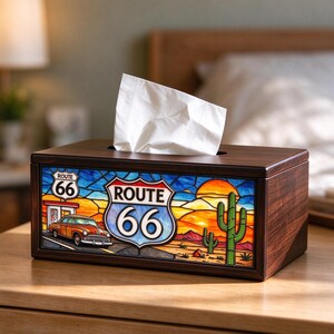 May include: A rectangular dark wood tissue box cover featuring a stained glass-style front panel. The design depicts a Route 66 road sign, a vintage orange car, a desert landscape with cacti, and a sunset. A white tissue is pulled through the top slot.