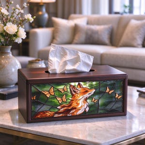 May include: A rectangular wooden tissue box cover featuring a stained glass panel on the front. The panel displays an orange and white fox surrounded by several small orange butterflies against a dark green, webbed background pattern.