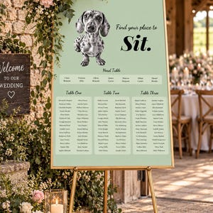 Puede incluir: Un cartel de distribución de mesas de boda en color verde salvia con marco dorado, que presenta una ilustración en blanco y negro de un perro salchicha y el texto Find your place to Sit. Lista nombres bajo Head Table, Table One, Table Two y Table Three.