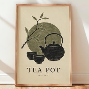 May include: A framed wall art print featuring a black teapot and two small cups, a leafy branch, and a large olive green circle on a cream background. The text TEA POT and tea ritual are printed in black at the bottom of the rectangular composition.