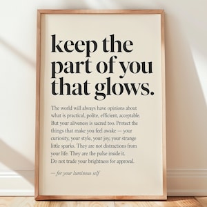 Może przedstawiać: Prostokątny plakat ścienny w jasnej drewnianej ramie z czarnym tekstem na kremowym tle. Tekst brzmi: keep the part of you that glows. The world will always have opinions about what is practical, polite, efficient, acceptable.