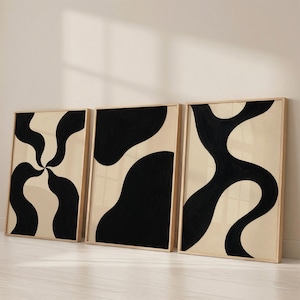 May include: A set of three rectangular wall art prints in light wood frames. Each print features a cream background with bold, black abstract shapes. The first print shows a swirling pattern, while the other two display large, organic, flowing forms.
