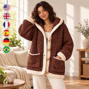 May include: A chunky, dark brown crochet hooded cardigan featuring a thick cream-coloured border, long sleeves with cream cuffs, two large front pockets, and four wooden toggle buttons down the centre front closure.