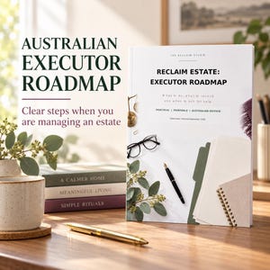 May include: A white book titled Reclaim Estate: Executor Roadmap with black text, a gold scale icon, black glasses, a black pen, and green eucalyptus leaves on the cover. The book is displayed on a wooden surface with a gold pen and stacked books.