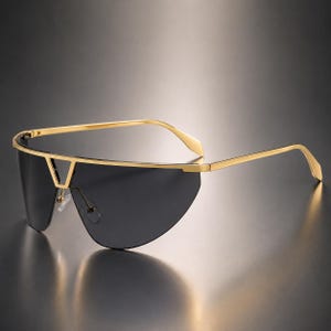 May include: Shield sunglasses featuring a single continuous dark grey lens and a thin gold-tone metal frame. The design includes a prominent gold bridge detail, slender gold temples, and adjustable nose pads for a secure fit.