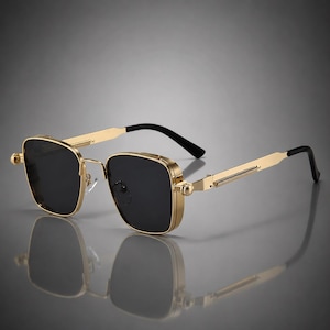 Puede incluir: Gafas de sol de montura cuadrada con estructura de metal en tono dorado pulido y lentes de color negro oscuro. Las patillas presentan un detalle texturizado similar a un resorte cerca de las bisagras, con puntas acabadas en plástico negro liso.