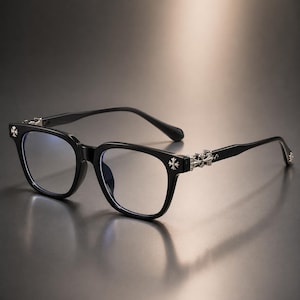 May include: Black-framed eyeglasses featuring a square lens shape and silver-toned cross emblems on the outer corners of the frames and along the temples. The temples display intricate silver-toned metal detailing near the hinges.