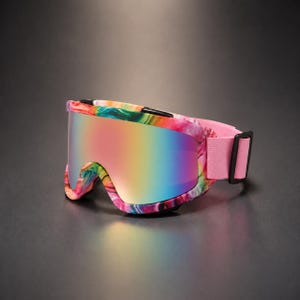 Pode incluir: Óculos de esqui com armação multicolorida marmorizada com redemoinhos em rosa, azul, amarelo e verde. A lente tem um acabamento reflexivo e iridescente que alterna entre tons de rosa e azul. Uma tira elástica rosa claro lisa está fixada.