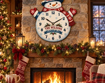 Puede incluir: Un reloj de pared redondo con forma de muñeco de nieve que incluye un sombrero azul, manoplas rojas y una bufanda roja. La esfera muestra números negros, copos de nieve y el texto THE WILSONS WARM WINTER WISHES en letras rojas y azules.
