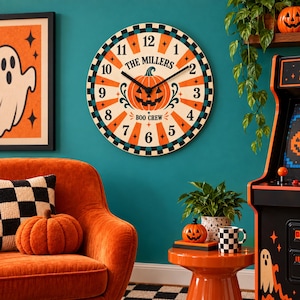 May include: A round wall clock featuring a central orange jack-o'-lantern graphic, black clock hands, and the text "THE MILLERS" and "BOO CREW". The clock face has a sunburst pattern in orange and cream with a black and teal checkered border.