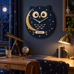 May include: A circular dark blue wooden wall clock shaped like an owl with large gold eyes, a gold crescent moon, and gold star accents. The clock features gold hands and a rectangular nameplate at the bottom with the name NOAH printed in black.