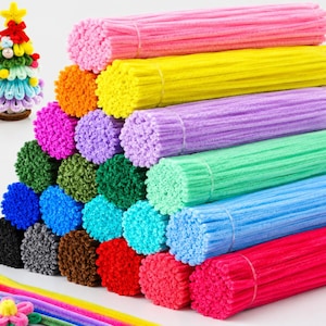 May include: A large collection of fuzzy pipe cleaners arranged in multiple bundles of various solid colors including pink, yellow, orange, purple, green, blue, red, black, and gray, alongside a small decorative tree and a flower craft.