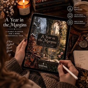 Könnte beinhalten: Ein digitaler Jahresplaner mit dem Titel A Year in the Margins auf einem Tablet-Bildschirm. Das Cover zeigt einen gotischen Steinbogen mit Blick auf eine verschneite Landschaft, herbstliches Laub, eine kleine Tasse und das Starfall Studio Logo.