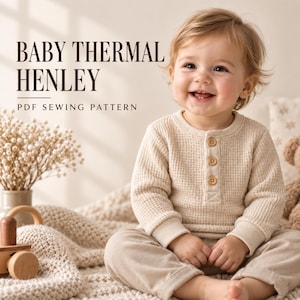 May include: A beige thermal henley shirt with long sleeves and three wooden buttons at the neckline. The text BABY THERMAL HENLEY PDF SEWING PATTERN is displayed in dark brown lettering on the left side of the image.