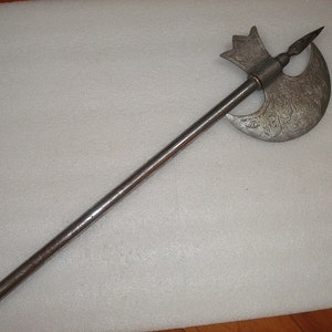 May include: A silver axe with a decorative handle and a crescent-shaped blade. The blade is decorated with intricate patterns.