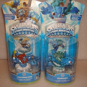 May include: Two Skylanders Spyro's Adventure figures in their packaging. The figures are blue and green and are in a clear plastic container. The packaging is blue and white and has the Skylanders logo on it. The text on the packaging says "Lightning Rod" and "Warnado".