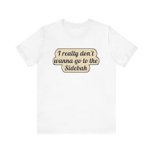 May include: A white short-sleeved t-shirt featuring a centered graphic with a tan, rounded rectangular background and a dark brown border. The text reads, "I really don't wanna go to the Sidebah" in a dark brown, cursive-style font.