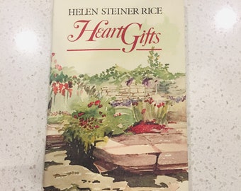 Pode incluir: Um livro intitulado "Heart Gifts" de Helen Steiner Rice. A capa apresenta uma pintura em aquarela de um jardim com um caminho de pedra e flores vermelhas.