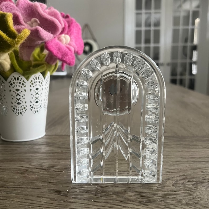 May include: A clear glass decorative object shaped like an arched doorway with a textured surface. The object has a circular opening in the center.