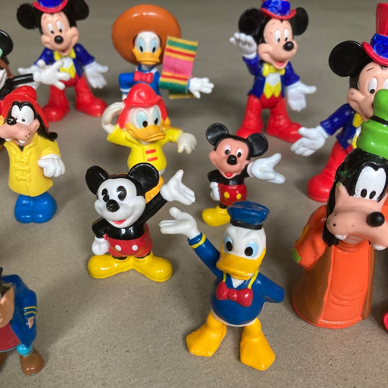 May include: A collection of vintage Disney character figurines, including Mickey Mouse, Minnie Mouse, Donald Duck, Goofy, and Pluto. The figurines are made of plastic and are painted in bright colors. They are all in good condition and would make a great addition to any Disney fan's collection.