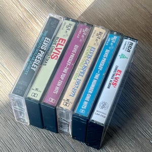 May include: A collection of six vintage Elvis Presley cassette tapes. The tapes feature album titles like "Blue Christmas" and "The Million Dollar Quartet." The cassette cases are clear, and the labels display the RCA logo.
