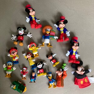 May include: A collection of 15 colorful plastic Disney character figurines, including Mickey Mouse, Donald Duck, Goofy, and Pluto. The figurines are all in various poses and are made of a durable plastic.