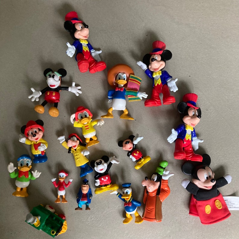 May include: A collection of 15 colorful plastic Disney character figurines, including Mickey Mouse, Donald Duck, Goofy, and Pluto. The figurines are all in various poses and are made of a durable plastic.