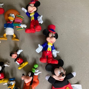 May include: A collection of vintage Disney character figurines, including Mickey Mouse, Donald Duck, and Goofy. The figurines are made of plastic and are painted in bright colors. They are in good condition and would be a great addition to any Disney fan's collection.