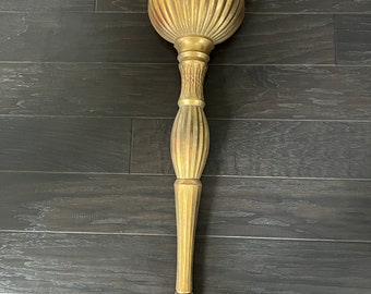 May include: A gold-colored wall-mounted planter with a fluted design. The planter has a wide, round top and a long, slender stem.