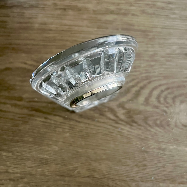 May include: A clear plastic shower head with a silver metal ring around the base.