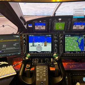 May include: A flight simulator cockpit setup featuring a large curved monitor displaying a runway view, two central avionics screens, a black yoke controller with green buttons, a white mechanical keyboard, and a secondary monitor showing flight data.