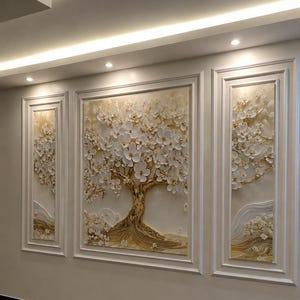 Puede incluir: Un conjunto de arte mural en tríptico con tres paneles enmarcados que presentan una escultura en relieve de un árbol con flores blancas y detalles dorados. El panel central es más grande que los laterales, todos con un diseño floral texturizado.