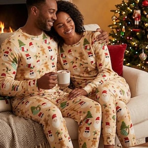Könnte beinhalten: Passende langärmelige Schlafanzüge in hellem Beige mit einem sich wiederholenden Muster aus Weihnachtsmännern mit Sonnenbrillen, grünen Weihnachtsbäumen und Lebkuchenmännern, bestehend aus Oberteilen mit Rundhalsausschnitt und Hosen.