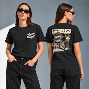 Puede incluir: Una camiseta negra con un pequeño logotipo blanco de Daft Punk en el pecho. La parte posterior muestra un gráfico grande con dos cascos de robot, texto en japonés y las palabras "AKA DAFT PUNK", "ORIGINAL FROM 1993" y "MEGA HITS" en círculos rojos.