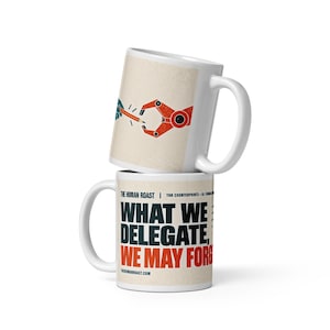 Pode incluir: Duas canecas de cerâmica branca empilhadas verticalmente. A caneca superior apresenta um gráfico de uma mão azul e uma garra robótica vermelha alcançando um lápis. A caneca inferior exibe o texto "WHAT WE DELEGATE, WE MAY FORGET" em letras pretas e vermelhas.