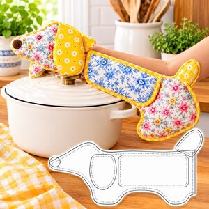 May include: A dachshund-shaped oven mitt featuring a mix of yellow, blue, and pink floral patterns with a yellow daisy print on the ears. The mitt has a brown nose detail and yellow trim. A white line drawing of the dachshund pattern is included.