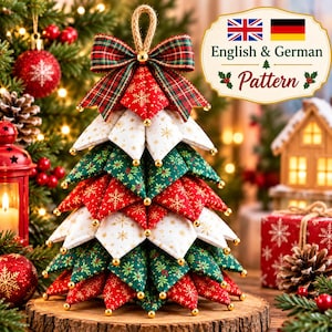 Peut inclure: Un ornement de sapin de Noël en tissu composé de segments triangulaires matelassés superposés en rouge, blanc et vert avec des motifs de flocons et de fleurs dorés. Le sapin est surmonté d'un nœud écossais et d'une boucle en jute.