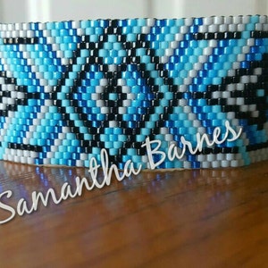 May include: A blue, white, and black beaded bracelet with a geometric pattern. The bracelet has the name "Samantha Barnes" written on it.