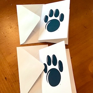 May include: Two white envelopes with blue paw print designs on the front. The paw prints are dark blue and have five toes.