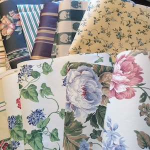 May include: A collection of vintage wallpaper rolls with various floral and patterned designs. The rolls are in different colors, including green, brown, white, and yellow.