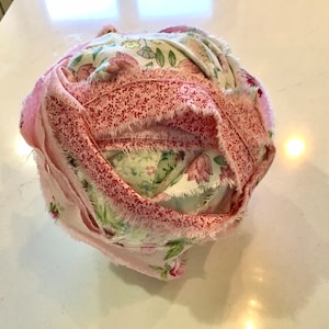 May include: A pink and white fabric ball with a floral pattern. The fabric is frayed and has a rustic look.