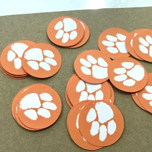 May include: A pile of orange and white paw print stickers. The paw prints are white on an orange background.