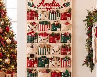 Könnte beinhalten: Ein hängender Adventskalender aus Stoff mit dem oben in Rot eingestickten Namen Amelia. Er verfügt über vierundzwanzig einzelne Taschen, die jeweils nummeriert und mit verschiedenen weihnachtlichen Mustern in Rot, Grün und Creme verziert sind.